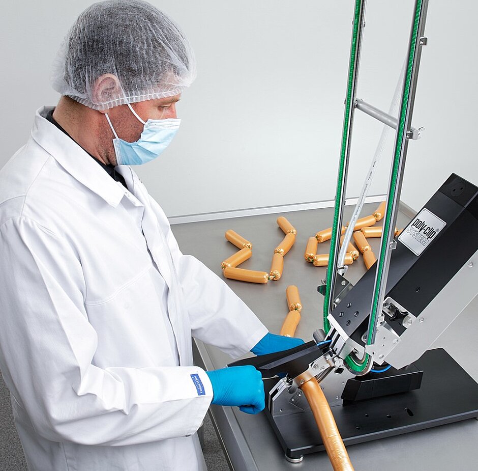 Butcher working with semi-automatic clipping machine